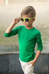 Stylish little boy in sunglasses and fashionable clothes .
