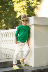 Trendy boy in sunglasses . He is very stylishly dressed .
