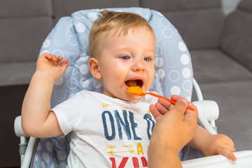 Baby boy eating lunch on the high chair