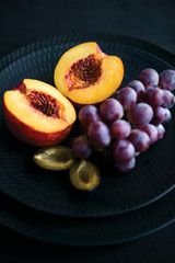 Fresh fruits on the black dish and black background.
