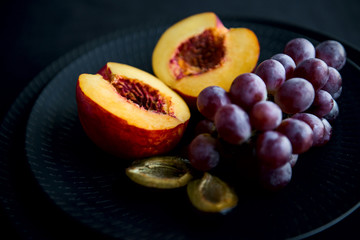 Fresh fruits on the black dish and black background. 