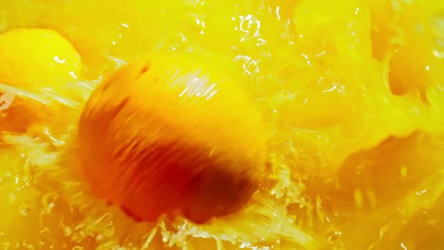 Closeup of three whole oranges falling down in fresh juice one by one in slow motion