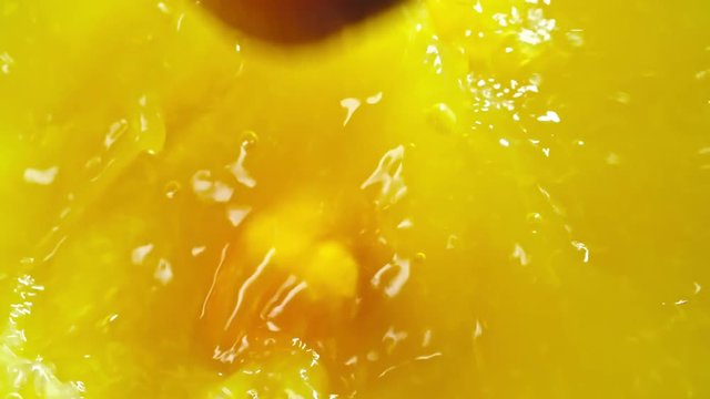 Closeup of three whole oranges falling down and splashing in freshly squeezed juice in slow motion