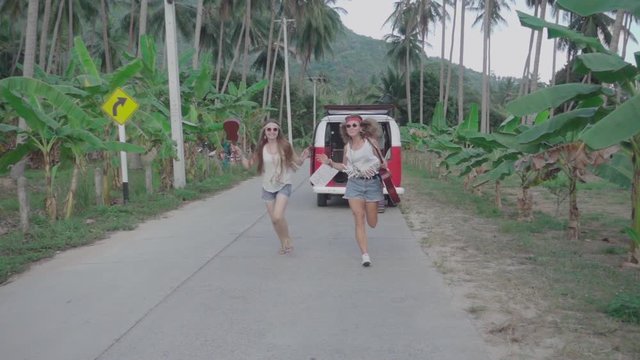 Hippie Girls Running Down a Road with Guitars in Their Hands. Slow Motion