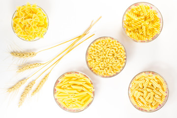 Five glass cups of pasta. wheat spikelets. White background