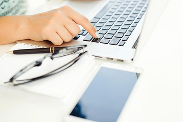 Close-up of female hands typing on laptop keyboard. Woman's hand