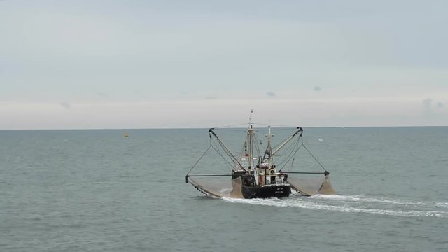 WIDE ungraded shot of shrimp fishing trawler moving towards the horizon