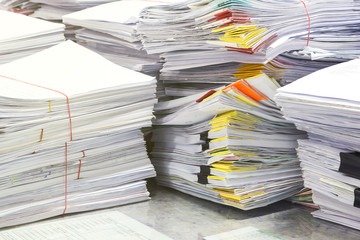 Pile of papers laid overlap on the desk in office.