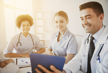 happy doctors with tablet pc meeting at hospital