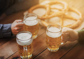 close up of hands with beer mugs at bar or pub