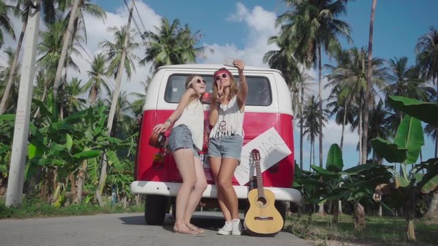 Smiling Hippie Girls with Mobile Phone Make Selfie near Red Minivan. Slow Motion