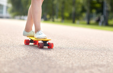close up of female feet riding short skateboard