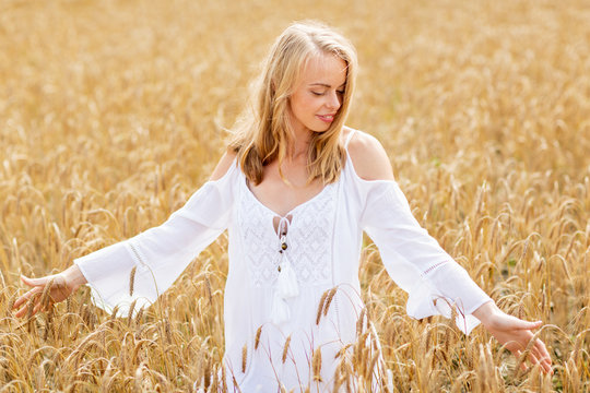 smiling young woman in white dress on cereal field