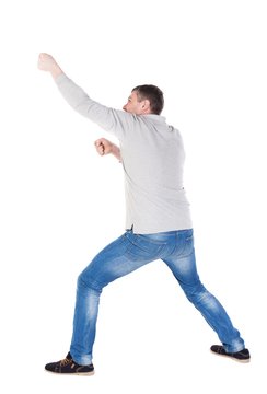 Back View Of Standing Man Pulling A Rope From The Top Or Cling To Something. Guy Watching. Rear View People Collection.  Backside View Of Person.  Isolated Over White Background. Legs Apart Man Pulls