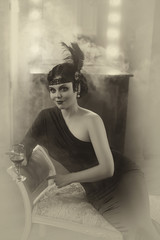 Beautiful Flapper girl with wineglass. Old photo in a retro style. Smoky eyes, hairstyle cold wave....