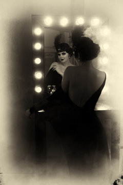 Beautiful Flapper girl looks in the mirror. Old photo in a retro style. Smokey eyes, hairstyle cold wave.