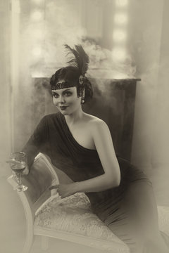 Beautiful Flapper girl with wineglass. Old photo in a retro style. Smoky eyes, hairstyle cold wave. Creative colors