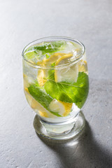 Refreshing lemonade with mint leaves and ice on gray stone table