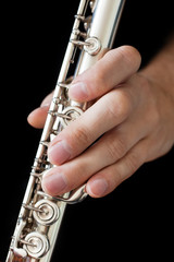 Obraz premium Flute in the musician's hands on a black background closeup