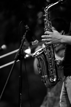 Saxophone in the hands of a musician at a concert in black and white