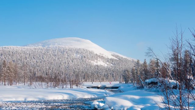 Finland. Sunny winter's day. The forest and hill. Skiers on the ice of a frozen lake. Time lapse UHD