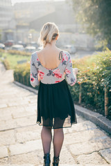 Obraz premium From behind view of young beautiful blonde woman walking outdoor in the street of the city