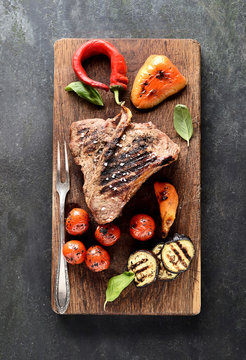 grilled beef steak on a cutting board on a black background