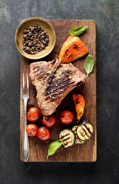 grilled beef steak on a cutting board on a black background