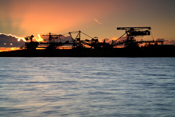 Excavators on abandoned Open Pit Mine by Lake at Sunset
