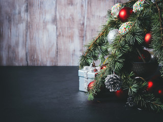 Blue spruce branches with christmas baubles on dark black and wooden background. Copy space