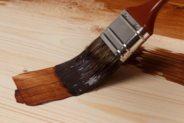 Brush on can of brown paint on partly painted wood, close up, lo