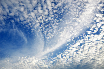 Fluffy and wispy white cirrus clouds in a deep blue summer sky