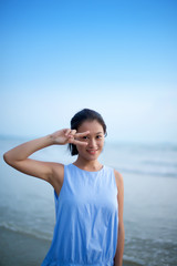 Asian girl making a scissors gestures at a beach