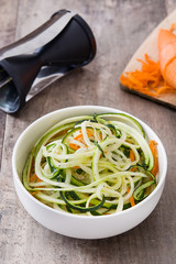 Carrot and zucchini noodles on wooden table

