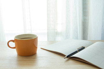 calendar planner or notebook papers with coffee on wood table in the morning, natural day light, selective focus, space for copy