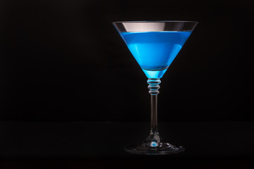 Blue curacao cocktail in martini glasses on black background