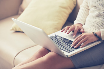 Naklejka premium Woman sitting on sofa and working on her laptop