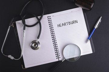 A note book with black ink pen written HEARTBURN word