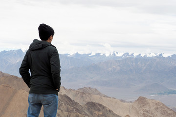 Young male traveler standing on the sand cliff thinking about or looking forward to something in Leh LadakhIndia