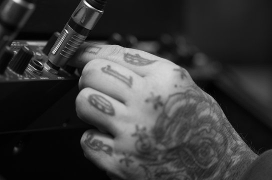 Closeup of hands covered with tattoos working on cable connection hardware audio box, studio equipment concept