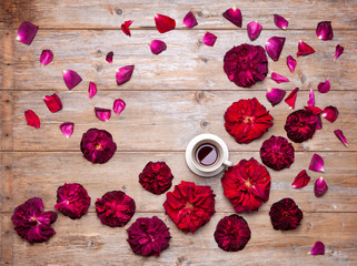 Top view of cup of black coffee and red garden roses with rose petals