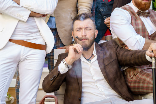 Portrait of elegant stylish successful man smoking cigar with friends