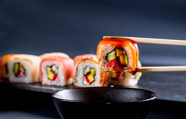 closeup with salmon roll, dipped in soy sauce