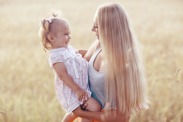 young mother hugging her daughter in a wheat field