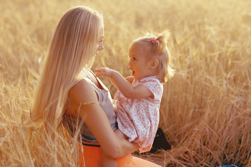 young mother hugging her daughter in a wheat field