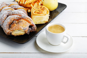 Cup of coffee and pastry on white wooden table