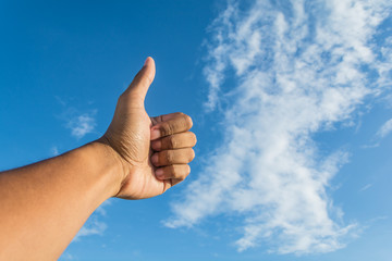 Asian man's thumb with bright blue sky and white cloud as backgr