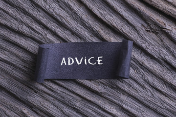 Advice word written on Black papper with wooden background. 