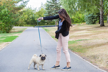 Sport girl and pug on a leash walk in the park