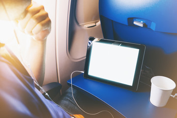 Side view of passenger traveler tourist using tablet at salon airplane. Female hands texting on gadget on background window aircraft, traveler trip concept, mockup blank screen computer with flare